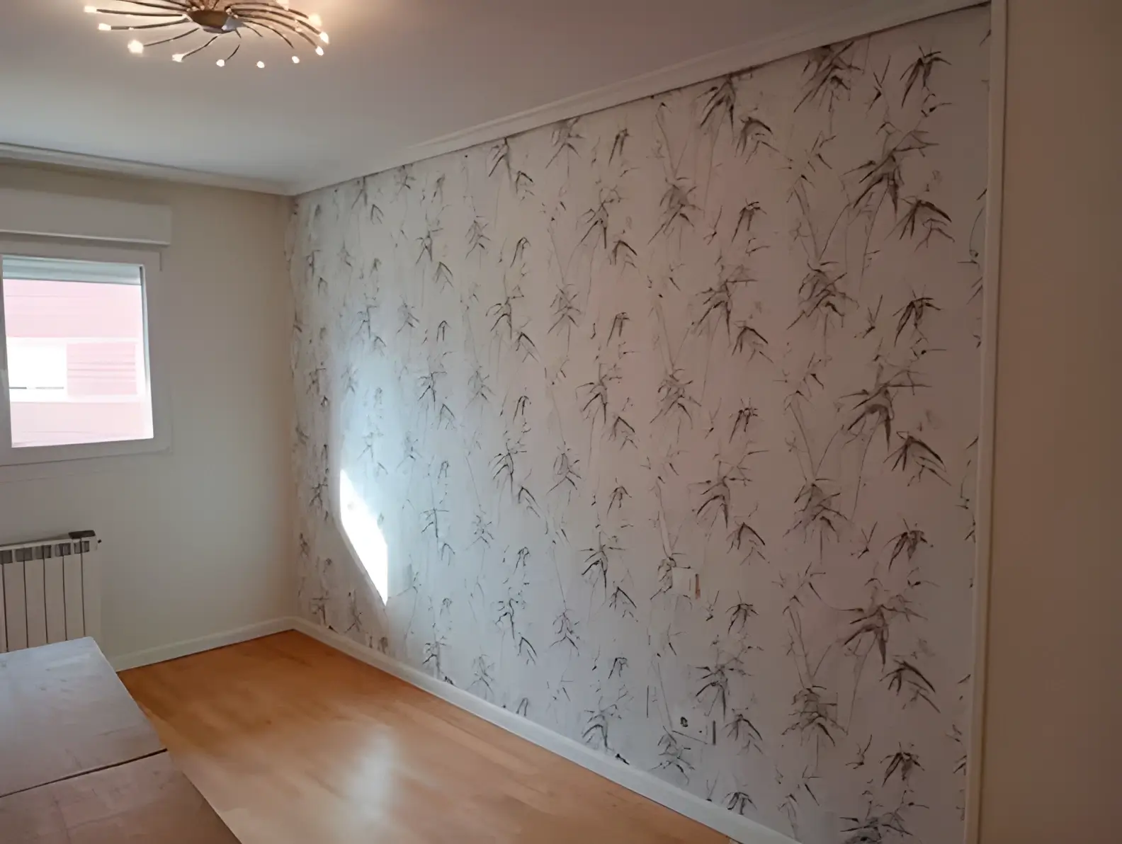 Los Pintores Ávila colocando papel pintado en pared de acento de habitación luminosa