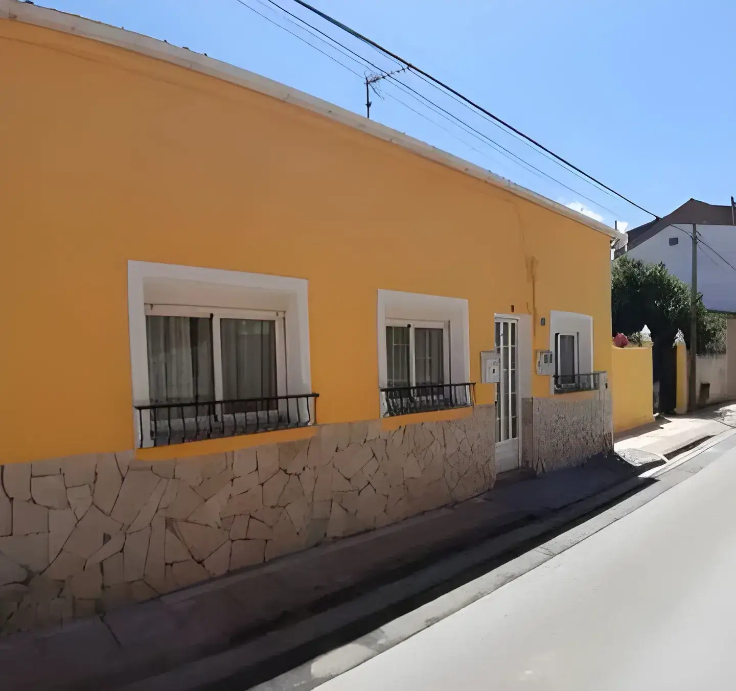 Los Pintores Ávila Fachada de casa tradicional pintada en color amarillo con zócalo de piedra